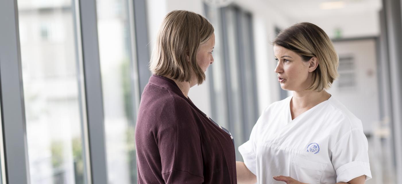 Sjukskötare talar med patient i korridor