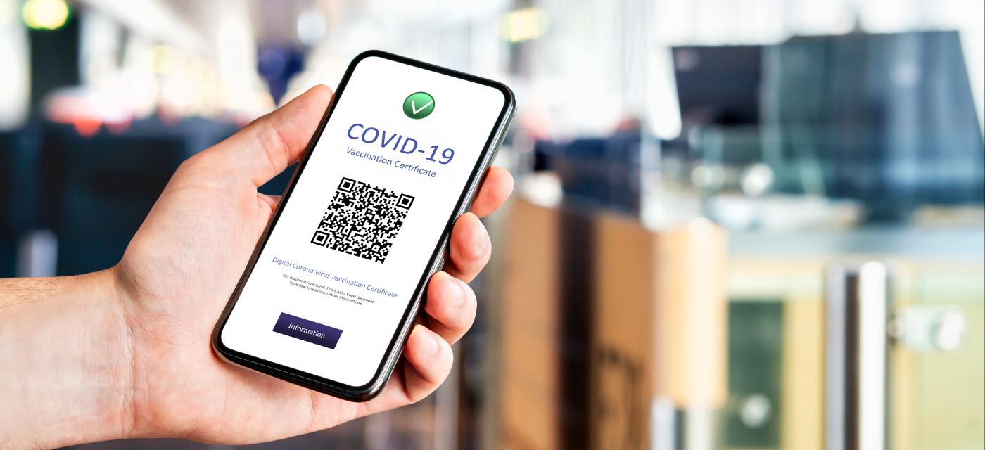 Hand som visar upp covidintyg i mobiltelefon