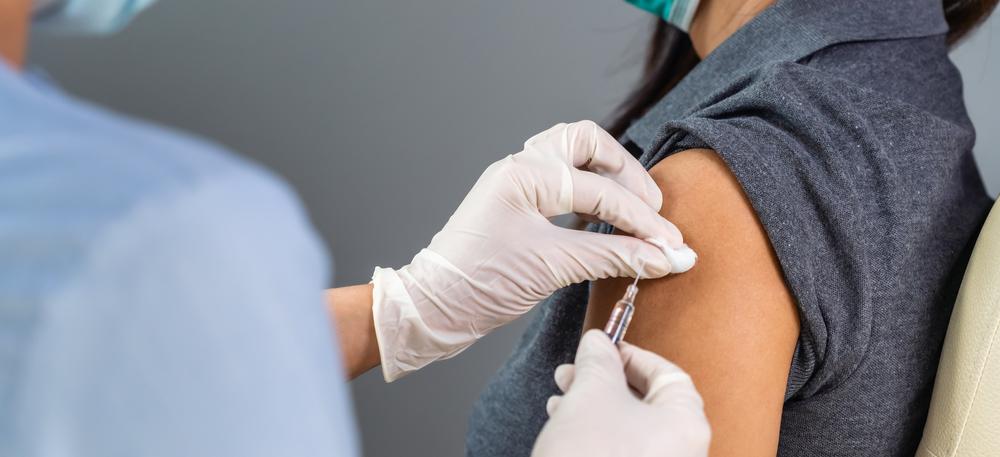 Kvinna med mask blir vaccinerad