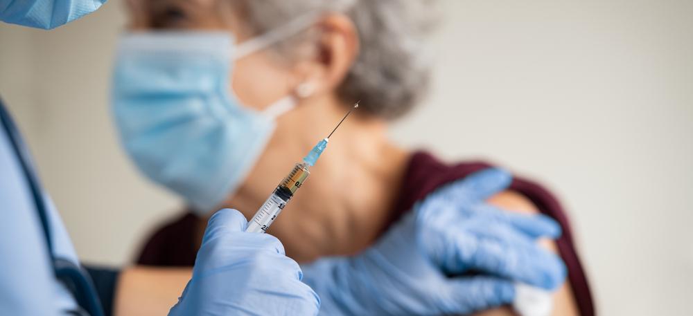 Äldre dam med ansiktsmask blir vaccinerad
