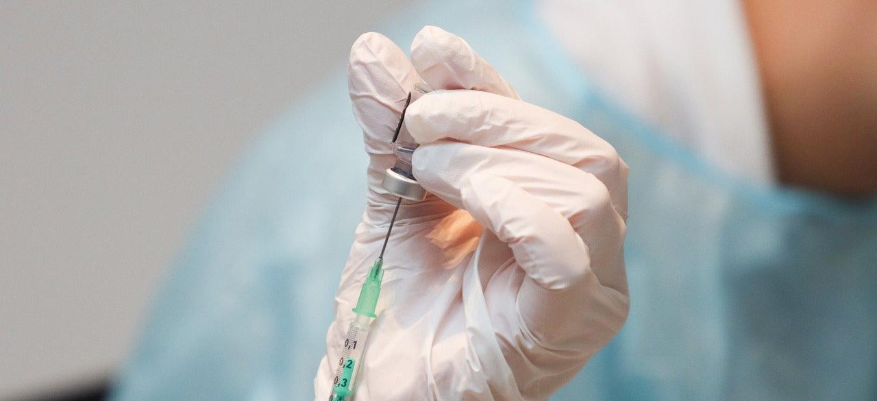 Handskklädd hand som håller i covid-19-vaccinationsspruta.