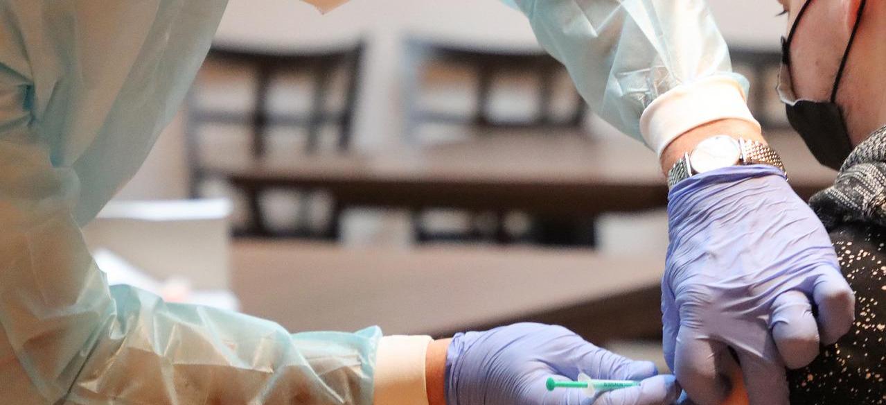 Sjukvårdare som vaccinerar patient med munskydd