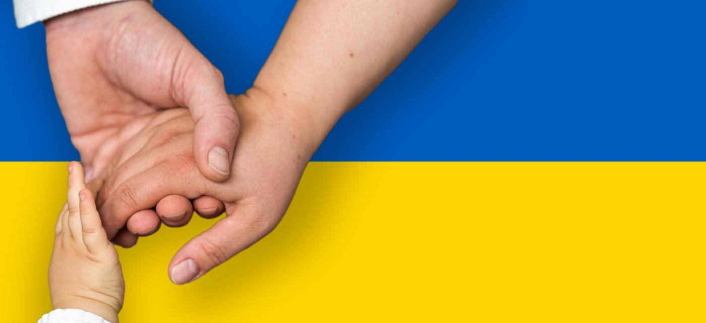 Händer i olika åldrar ovanför Ukrainas flagga
