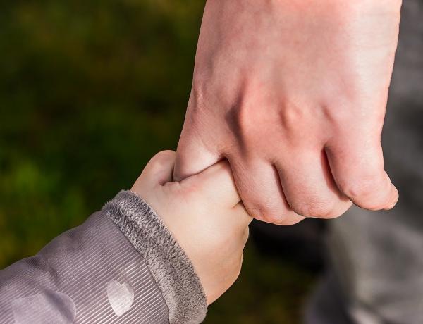 vuxen hand som håller i ett barns hand