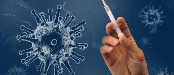 Detaljbild av hand som håller i vaccineringsspruta - blå bakgrund med stora coronavirus.
